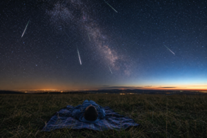 Bright meteor streaks crossing a star-filled night sky above a dark rural landscape during the Eta Aquarid meteor shower peak
